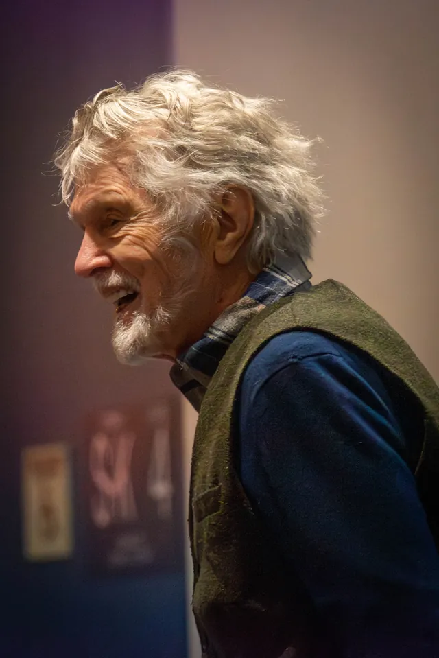 Tom Skerritt in profile, white-haired, laughing on stage in 2024