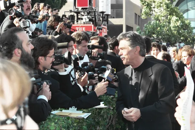 Tom Skerritt in a black suit facing a crowd of photographers and television cameras at the 1994 Emmy Awards