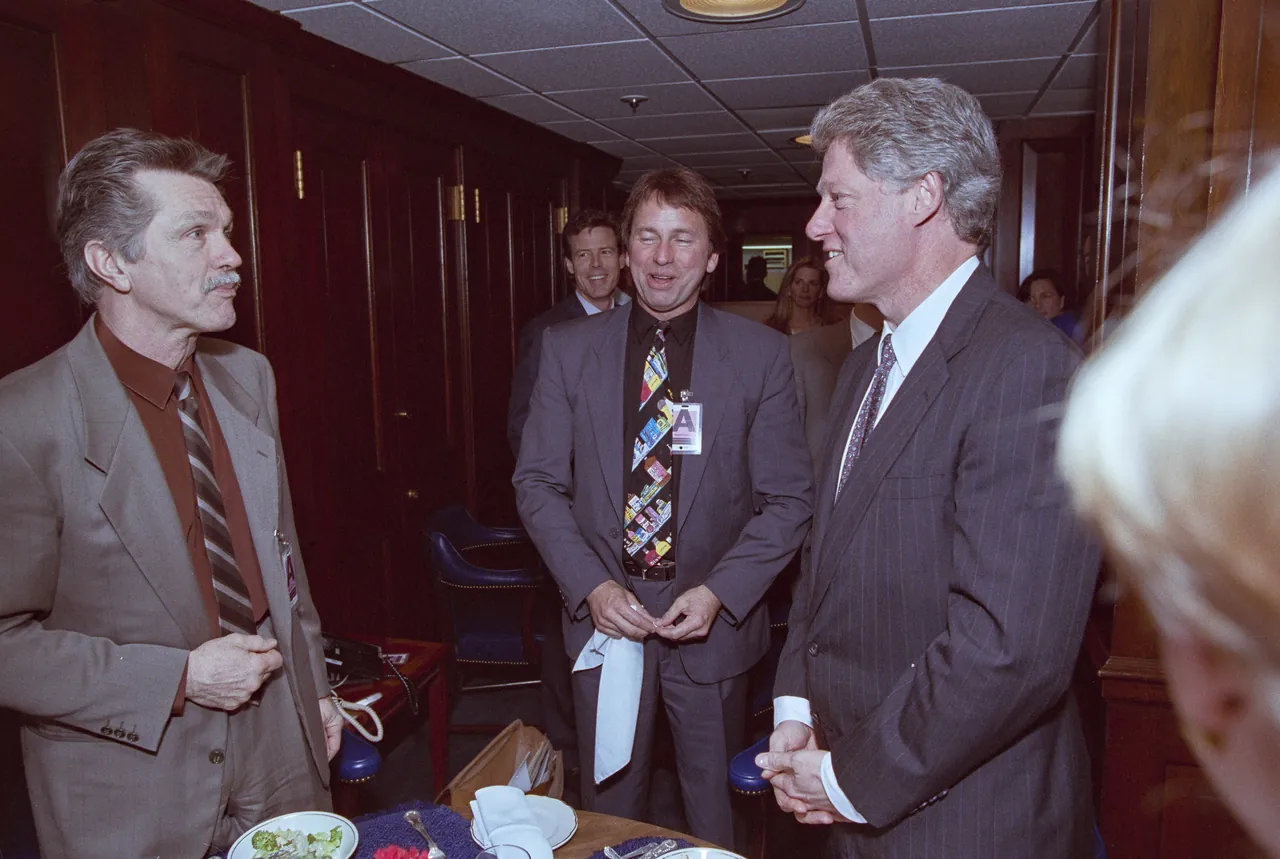 Tom Skerritt, with a mustache and a tan suit, talking with John Ritter and President Bill Clinton at the White House in 1993